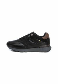 Scarpa sportiva nera in materiale sintetico e camoscio, con punta rotonda, chiusura con lacci e un accento marrone vicino al tallone.