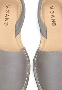 Gray vegan slip-on shoes with a smooth texture, featuring a stitched lighter accent around the edge and embossed brand name on the insole.