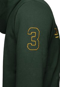 Sudadera verde con un número "3" amarillo bordado en la manga izquierda, con tejido texturizado y un ajuste informal.
