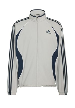 Veste zippée gris clair avec des accents bleu marine, présentant trois rayures sur les manches et un logo Adidas sur le haut à gauche. Texture de tissu lisse.