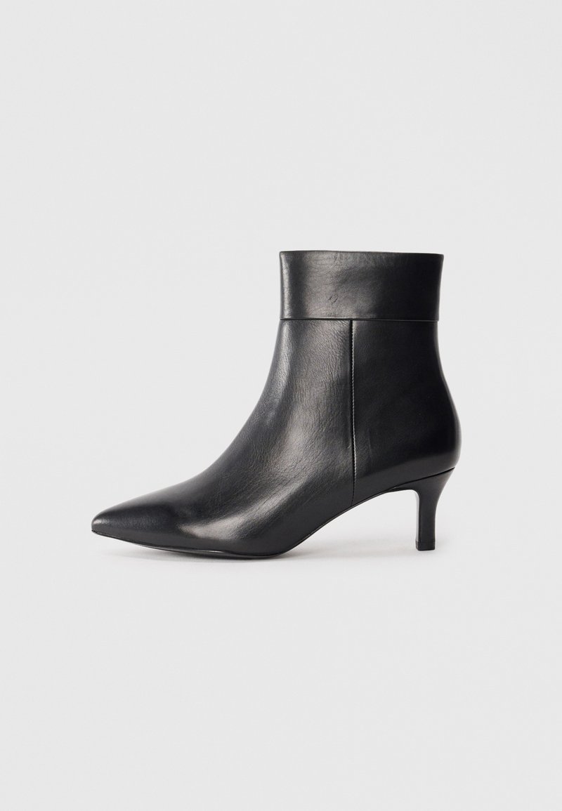Bottine noire en cuir à bout pointu avec un talon moyen fin et un détail de poignet plié sur fond blanc uni.