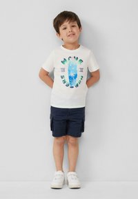 Weißes T-Shirt mit kurzen Ärmeln und buntem Surfbrett-Graphic sowie Text, kombiniert mit marineblauen Cargo-Shorts und weißen Sneakers.