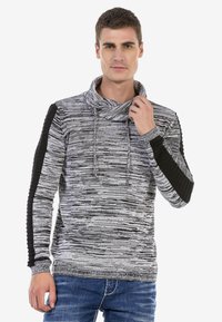 Grau und schwarz gestreifter Pullover mit einem Schalkragen, versehen mit gerippten schwarzen Akzenten an den Ärmeln und einem strukturierten Strickdesign.