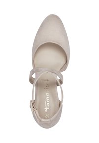 Beige suède schoen met een ronde neus, enkelbandje en cirkelvormige uitsnijdingen aan de zijkanten. Het interieur heeft gouden letters en een ritsluiting.