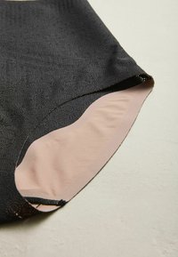 Black pattern fabric with a textured finish, featuring a smooth light pink lining at the bottom edge, showing a clean cut and seam.