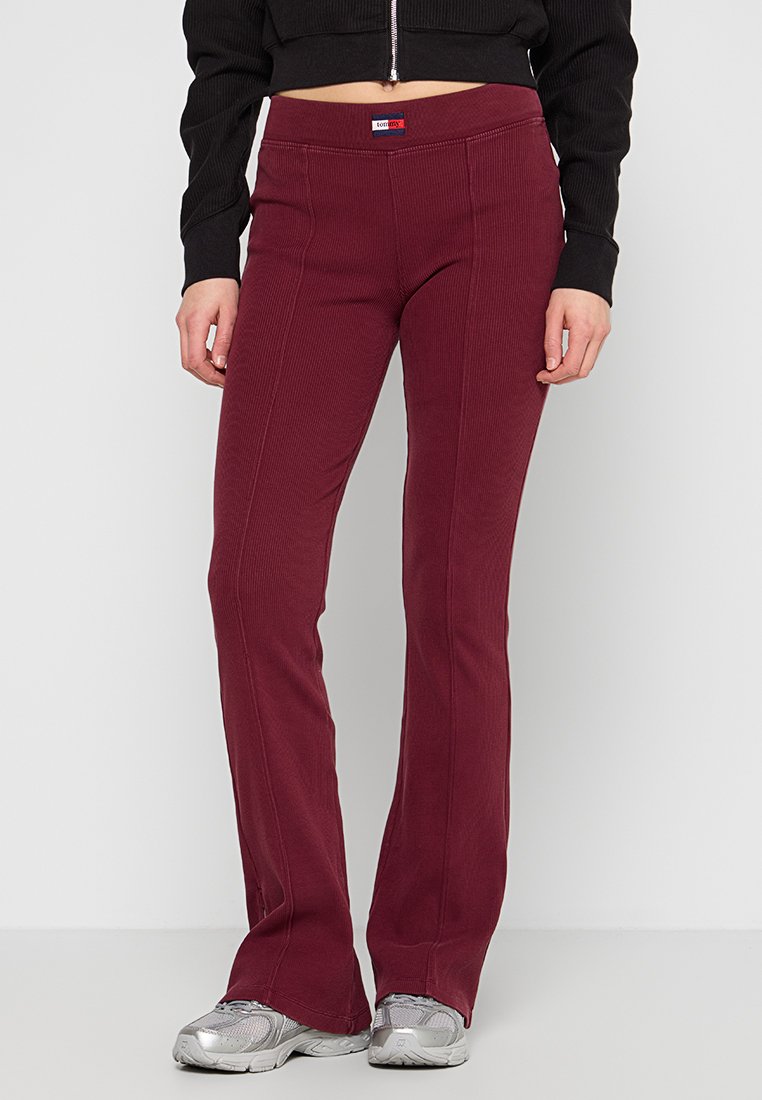 Bordeaux geklede broek met ribbeltextuur en tailleband, voorzien van verticale naden en een logo patch. Gemaakt van stretchy stof voor comfort.