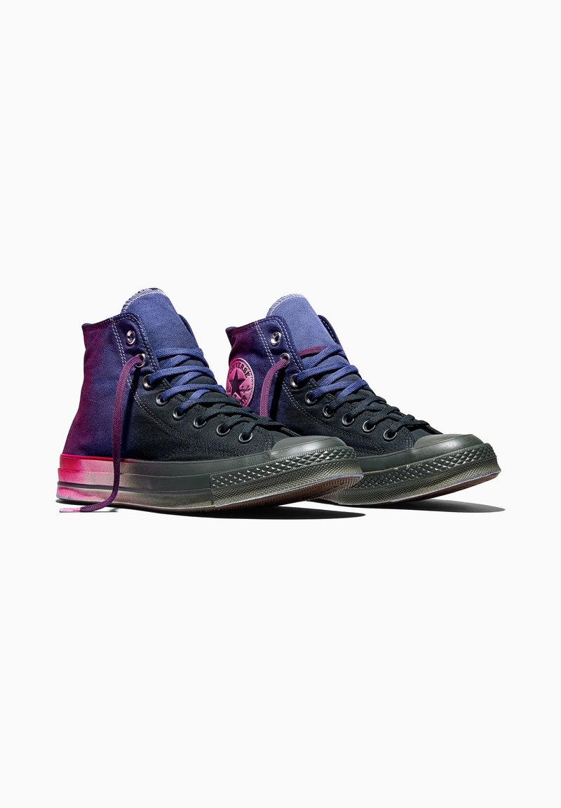 Paar dunkelblaue High-Top-Canvas-Sneaker mit schwarzen Sohlen und Schnürsenkeln, pinkes Converse-Logo-Patch an den Innenseiten, Vorderansicht.