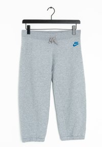 Šedé tepláky vyrobené z bavlněné směsi, vybavené elastickým pasem se šňůrkou, manžetami na kotnících a modrým logem Nike na přední straně.
