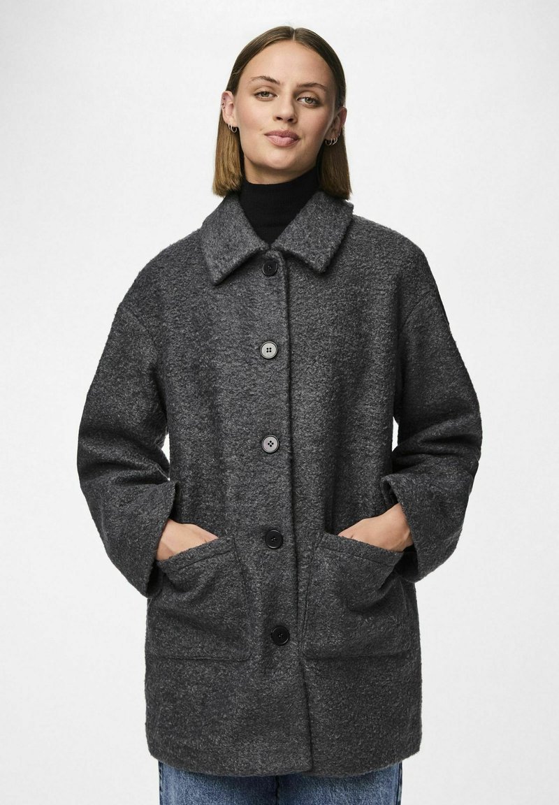 Cappotto grigio in misto lana con colletto, ampie tasche frontali e chiusura a bottoni. Presenta una finitura testurizzata e maniche dal taglio loose.