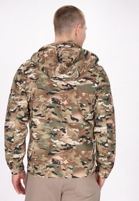 Camouflagejack met een capuchon, voorzien van een mix van groene, bruine en zwarte patronen. Glad materiaal en elastische manchetten ronden het ontwerp af.