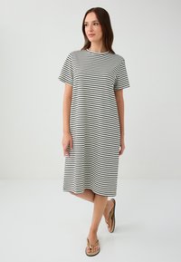 Robe à manches courtes rayée noir et blanc en tissu doux, avec un col rond et une coupe ample, arrivant au genou.