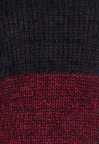 Sweter dzianinowy z ukośnym podziałem; górna część w ciemnoszarym kolorze, dolna część w teksturowanej czerwieni. Miękki materiał z mieszanki wełny.