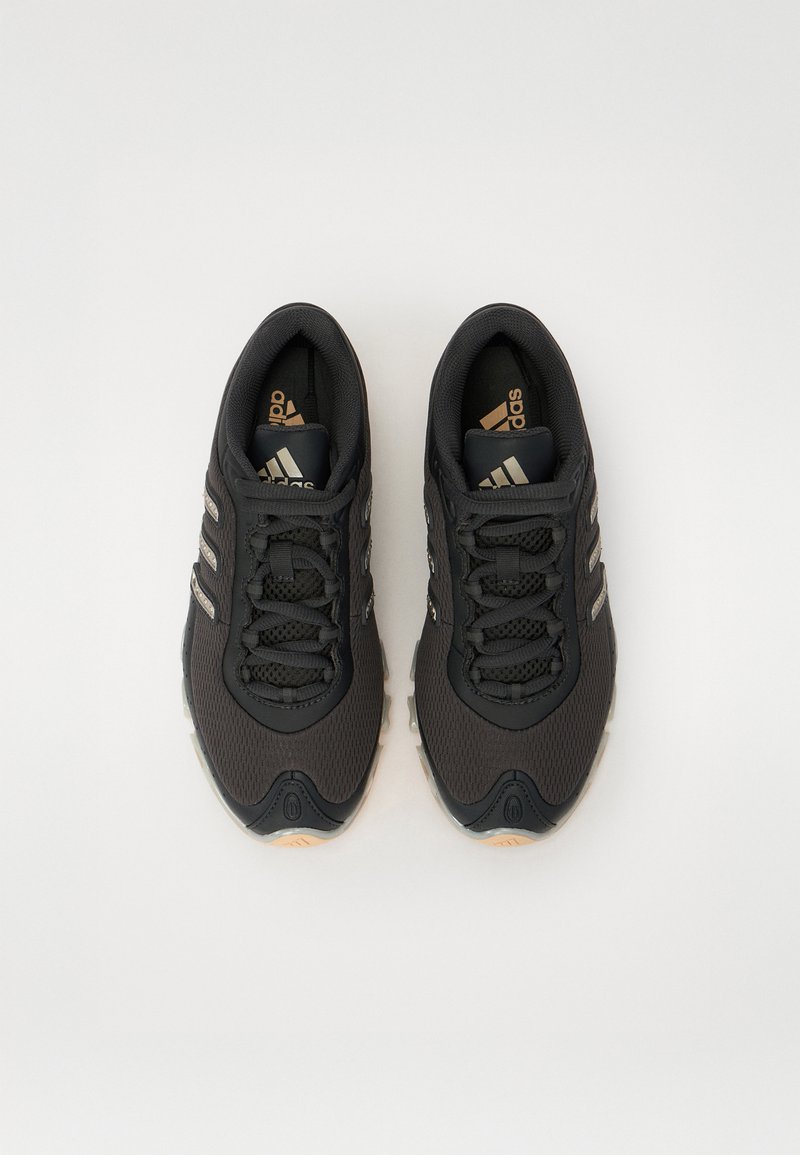 Zapatillas deportivas negras con parte superior de malla, que presentan tres acentos de rayas plateadas, suela texturizada y un cuello acolchado.