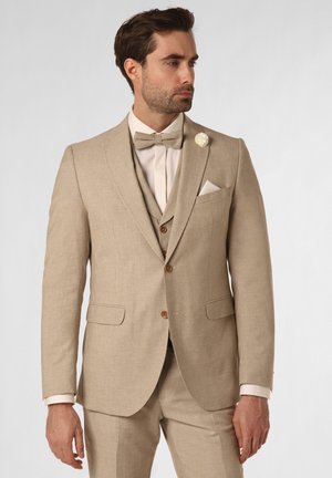 Beige Leinenanzug mit maßgeschneidertem Schnitt, ausgestattet mit einer Fliege, einem Einstecktuch und einer dezenten Blütenbrosche. Glatte Textur und strukturierter Schnitt.