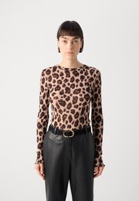 Langermet topp med leopardmønster i et mykt stoff, med brune flekker på en beige bakgrunn, kombinert med svarte høytaljede bukser og et gullbelte.