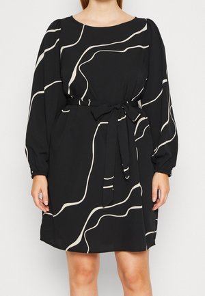 Czarna sukienka z długim rękawem z białymi, abstrakcyjnymi, zakrzywionymi liniami, dekoltem typu łódka, bufkami na rękawach i wiązanym paskiem z tkaniny w talii.