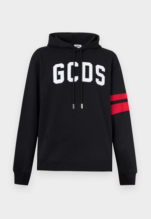 Čierna mikina s kapucňou s bielym nápisom "GCDS" na hrudi, červenými a čiernymi pruhmi na ľavom rukáve a čiernymi šnúrkami s brandovanými koncovkami.
