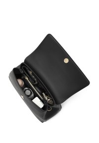 Black leather bag with a top flap and gold hardware. Interior contains compartments with cosmetic bottles and accessories.