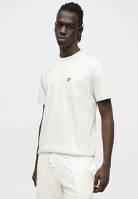 Light green short-sleeve t-shirt made of smooth cotton, featuring a chest pocket with a small yellow logo. Simple, relaxed fit design.