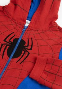 Roter und blauer Kapuzen-Overall mit einem Spinnennetzdesign, schwarzer Spinnen-Grafik auf der Vorderseite und blauen Reißverschlussakzenten. Weicher Stoff, gerippte Bündchen.