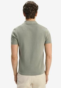 Kortärmad polo skjorta i ljusgrön ribbad väv, med klassisk krage och en figurnära silhuett. Slät yta, ren design.