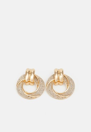 Guldtonede øreringe med sammenflettede cirkulære designs, den ene tekstureret med små sten, den anden glat med en snoet detalje.