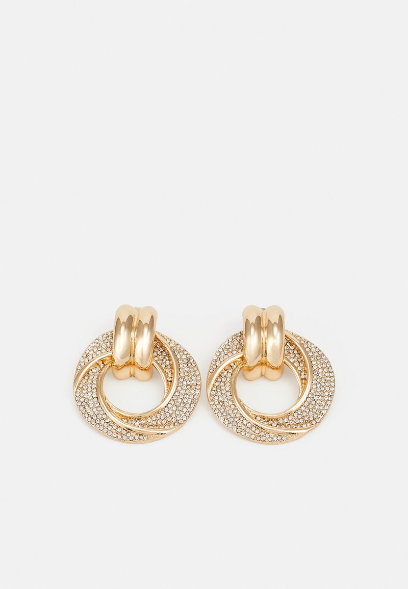 Gullfargede øreringer med sammenkoblede sirkeldesign, en teksturert med små steiner, den andre glatt med en vriDetalj.