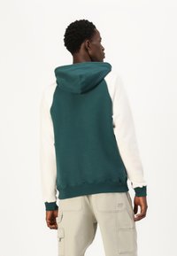 Hooded sweatshirt with teal back and white sleeves, made of soft fabric. Features ribbed cuffs and waistband, with a relaxed fit.
