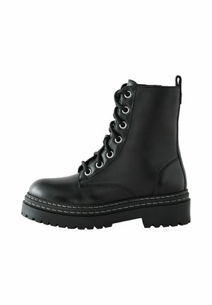 Botte chevillère en cuir noir à lacets, avec une pointe arrondie, une semelle épaisse et des coutures contrastées. Équipée d'œillets métalliques et d'une languette à l'arrière.
