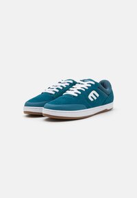 Teal skate shoes made of suede with white laces and branding. Features a padded collar and a gum rubber sole for grip and comfort.