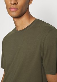 Olive green cotton t-shirt with a round neckline and short sleeves, featuring a smooth texture and no visible patterns or accents.
