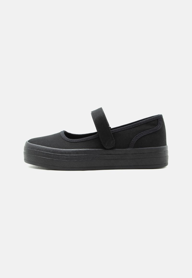 Chaussure Mary Jane noire avec semelle en caoutchouc épaisse et bride ajustable à fermeture Velcro, conçue pour un usage décontracté avec un bout arrondi.