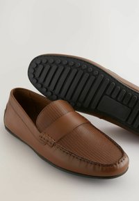 Brune læder loafers med vævet stropdetalje, tekstureret overdel og sort gummisål med grip-mønstre. Klassisk design.