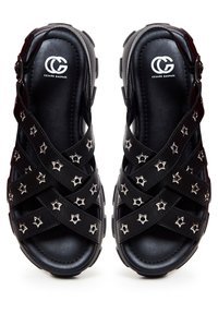 Zwarte sandalen met kruislingse banden versierd met zilveren stervormige studs. Gemaakt van leer; textuur van de voetbed; sluiting met een gesp aan de zijkant.