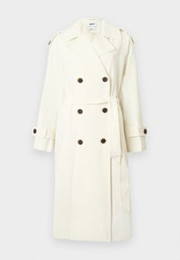 Trench-coat crème à double boutonnage avec boutons foncés, ceinture à la taille, épaulettes aux épaules et bracelets ajustables aux poignets.