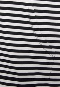Tecido listrado em preto e branco com uma textura suave, apresentando um bolso visível e costura contrastante.