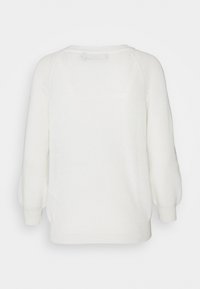 Valkoinen neulepusero, jossa on pyöreä kaula-aukko, pitkät puffihihat ja rento istuvuus. Tekstuurin näyttää olevan pehmeä ja mukava.