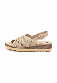 Sandelia beige con patrones florales recortados, correa ajustable, plantilla acolchada y suela de cuña estratificada con un acabado texturizado.