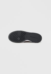 Talpă exterioară din cauciuc negru cu model circular și secțiuni ridicate. Prezintă un logo vizibil și detalii texturate pentru aderență.