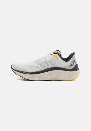 Hvid og grå New Balance løbesko med sorte og gule accenter, tekstureret sål mærket Fresh Foam og varemærket hælkappe.