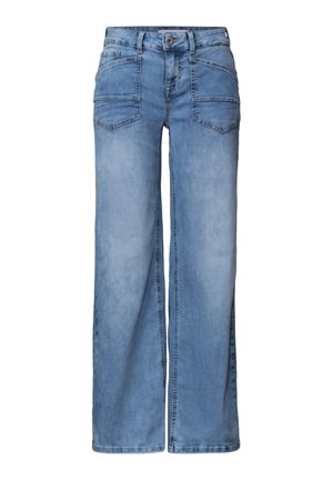 Person trägt blaue High-Waist-Jeans mit großen Vordertaschen, weißes hineingestecktes Hemd und eine teilweise geschlossene bordeauxrote Jacke.