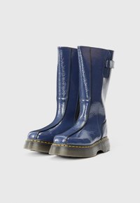 Μπλε πατινέ δερμάτινα μπότες μέχρι το γόνατο με στρογγυλή μύτη, παχύ εξωτερικό πέλμα, αντίθετο ραφές και λεπτομέρεια με λουράκι στο πλάι.