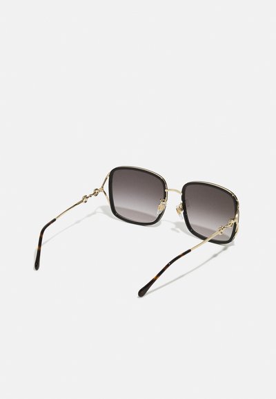 Sunglasses with large square frames, black and gold metal accents, dark gradient lenses, and tortoiseshell-patterned temples.
