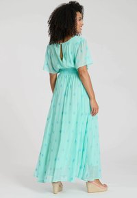 Ljusblå, flödande maxiklänning med smockad midja, korta svepande ärmar och nyckelhål i ryggen, prydd med små broderade detaljer.