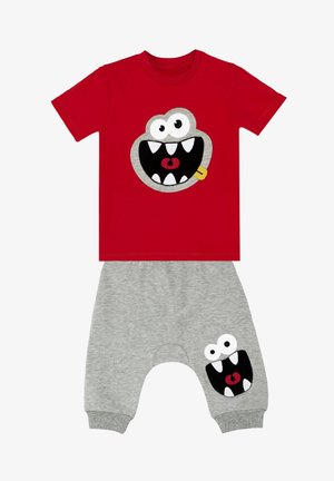 Rød bomulds t-shirt med et stort monsteransigt broderet, parret med grå sweatpants med en matchende monsteransigt patch på benet.