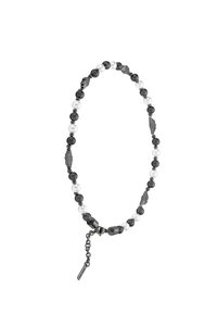 Zwart-witte kra necklace met glanzende en matte kralen, metalen accenten en een ketting met een label.