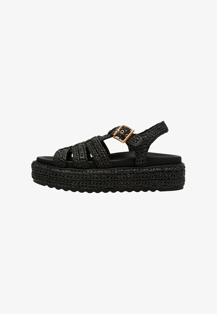 Black platform sandals with woven upper straps and a buckle accent. Textured sole with a thick woven base, offering significant elevation.