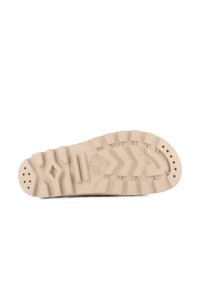 Suola di sneaker in gomma beige con motivi testurizzati e scanalature. Le caratteristiche includono perforazioni circolari e un ritaglio a forma di diamante.