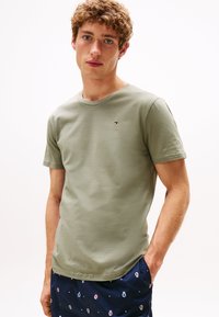 T-shirt in cotone verde oliva con maniche corte e scollatura rotonda, caratterizzato da un piccolo logo sul petto. Tessuto morbido, vestibilità comoda.