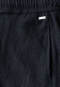 Námořnický plisovaný materiál s zvrásněnou texturou a elastickým pasem. Obsahuje stříbrnou visačku s nápisem "Cecil."